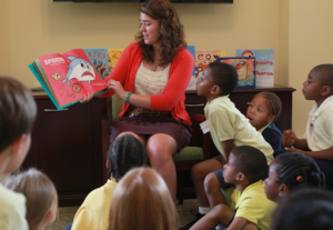 A class teacher is shown reading a picture book to her class.